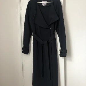 Tunn kappa  - En mörkblå kappa från Lager157 säljes i fint skick! En tunn kappa med knyte i midjan.