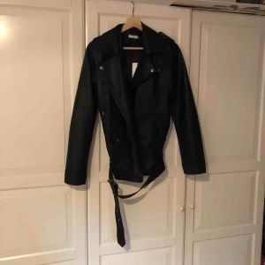  - Skinnjacka från Jacqueline de Yong, JdY, i storlek 34/XS, dock rymlig. Aldrig använd med prislapp på. Dragkedja och spänne nertill fungerar fint. Ej äkta skinn. Hund finns i hemmet