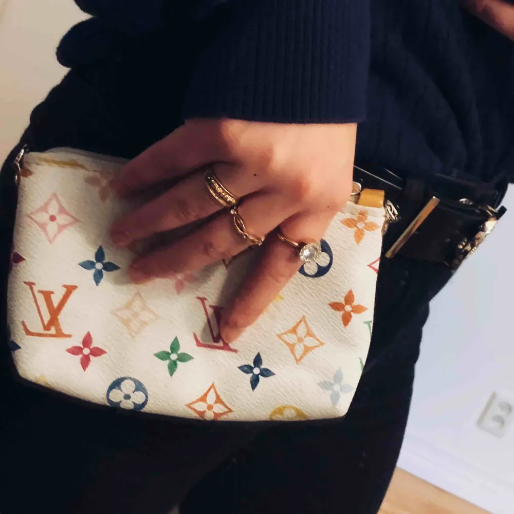 Fake Louis Vuitton väska där du får plats med mobil och plånbok. Perfekt att ha i handväskan och snygg. LV ”märken” i färg på en vit bakgrund. Köpare står för frakt. . Väskor.