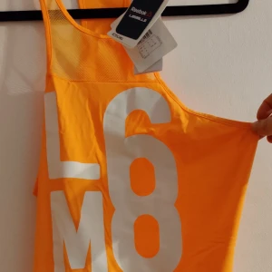 Nytt Reebok linne orange small - HELT NYTT tränings linne.  REEBOK.  84 % polyamid 16 % elastan.  Mjukt material med mesh hög krage.  Köparen står för frakten, fraktförslag mottages gärna.  Samfraktar. Fler bilder skickas om det önskas.