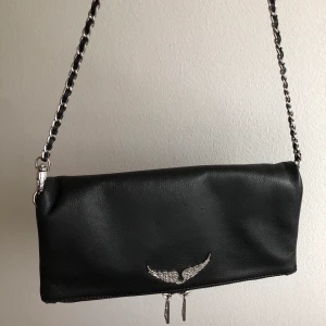 Zadig Voltaire Väska - Zadig Voltaire ”Rock Bag”, gjord i skinn med silver detaljer. Det finns två kedjor/ band man kan ta av och sätta på, finns på bilden. Både påse och dust bag finns och följer med köparen. En perfekt storlek för en dag på stan eller bara till skolan. Ord pris: 3265kr