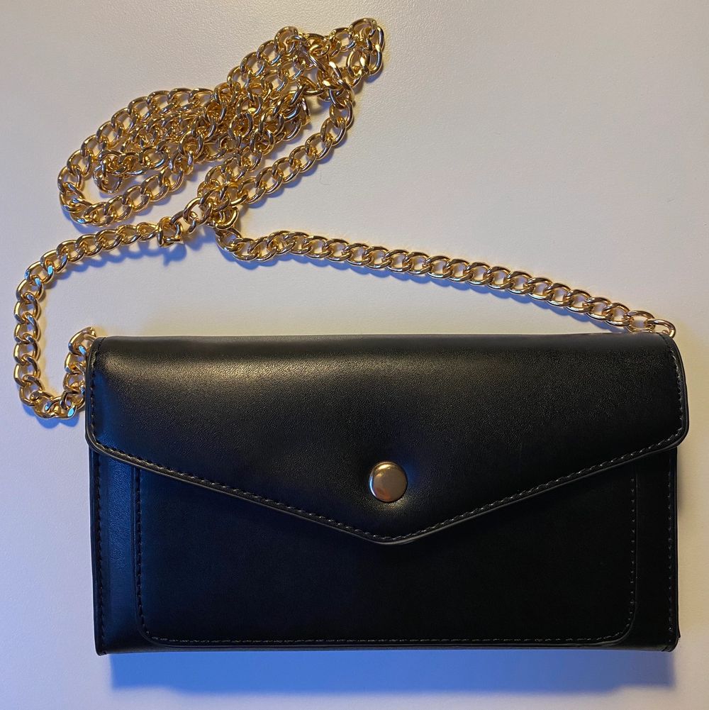 En svart handväska med borttagbar guldkedja. Väskor.