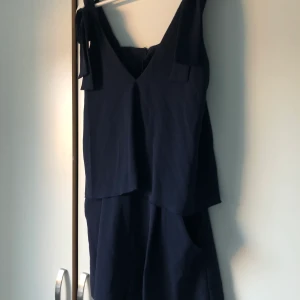 Playsuit öppen i ryggen marinblå  - Fin marinblå playsuit storlek 36. Öppen i ryggen, knyt detaljer i axlarna. knappt använd! 