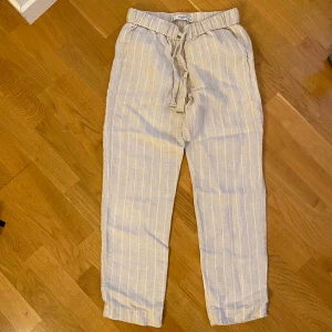 Beigea randiga linnebyxor  - Säljer dessa beigea linne byxor med vita ränder från Mango. Bra kvalitet och så snygga till sommaren! Är 167 och brukar ha 34/36 i byxor och dessa sitter bra förutom att de är en aning för korta