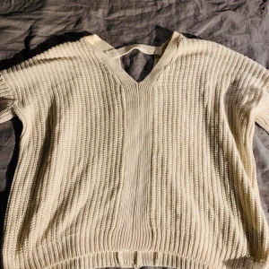 Oversize vit stickad tröja. Detalj bak - En vit stickad tröja med snygg detalj bak i nacken. Storlek L men är oversize. Använd ett antal gånger, inga skavanker vad jag kan se. 