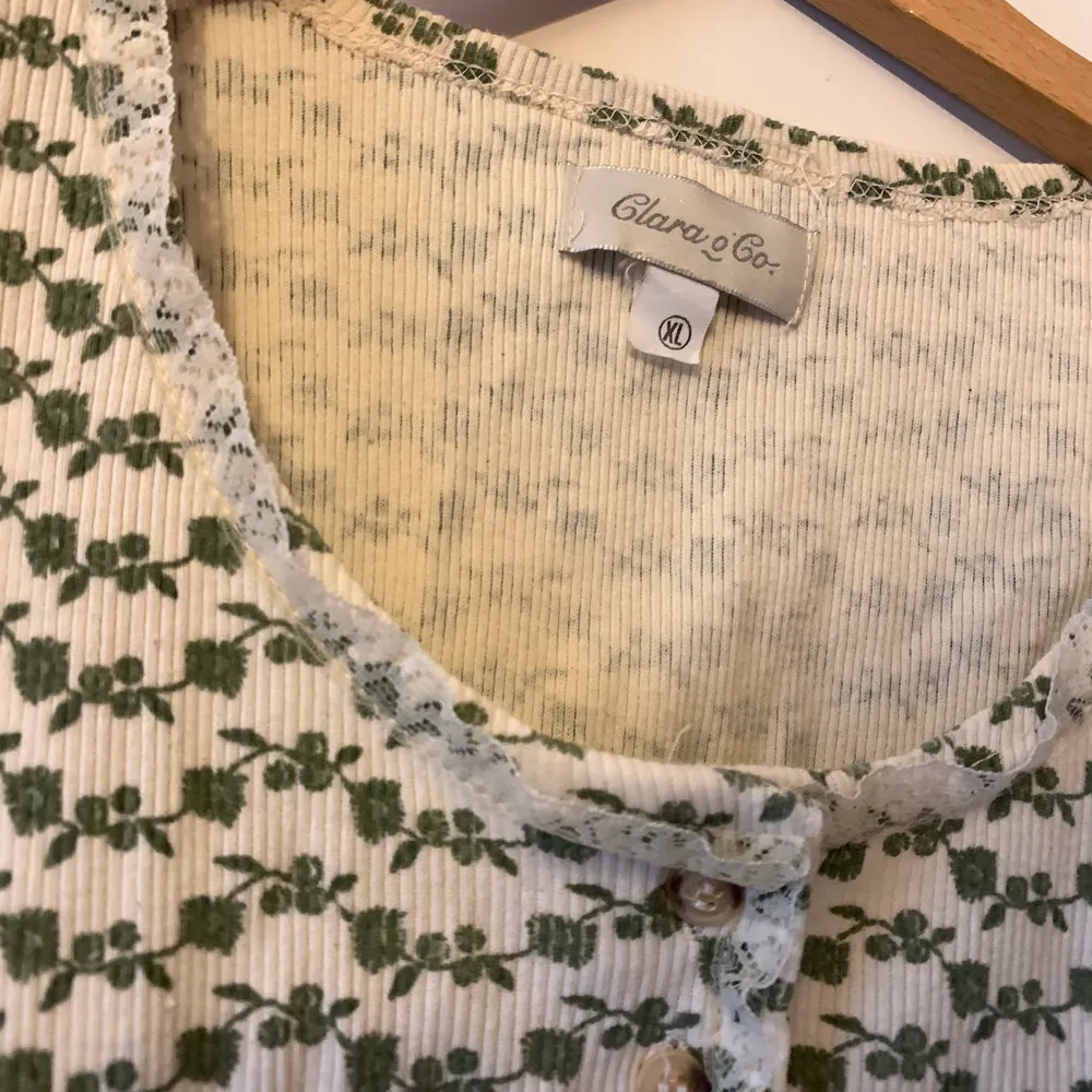 Vit ribbad tröja med gröna blommor på från 90-talet. Spetskant uppe vid halsen och den är i fint skick. Visas på en M. . T-shirts.