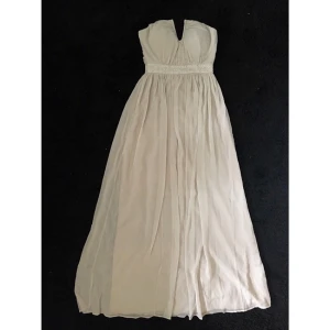  - Denna balklänning är helt oanvänd, bara provad på. Den är i helt nytt skick och hängt i skydande plastöverdrag sedan den var nyköpt. Bystens undersida är dekorerad med diamanter som fortsätter runt bakom ryggen. Bysten är även vadderad med kupor som en inbygd bh. Dragkedjan sitter längst ryggen. Klänningens färg är grå/silvrig aktig, köpt från Nelly.com iår. Nypris 899kr. Skriv vid intresse! 