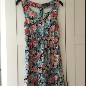  - Snygg blommig sommarklänning, med superfin öppen rygg med blixtlås. Den har svart "bakgrund" 