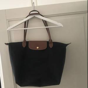 En jättefin longchamp väska i svart med bruna detaljer. Sparsamt använd! ✨🛍 såklart äkta. Litet märke under väskan av tuggumi eller liknande.