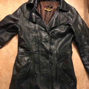  - Svinsnygg läderkappa. Lite sönder vid ena fickan, annars i toppskick. 