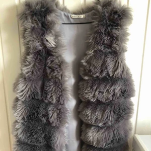  - Fin grå pälsväst från Tessie. Endast använd 1 gång så den är så gott som ny i väldigt fint skick utan några skador. Kan mötas upp i Borås eller frakta men då står köparen för frakten.