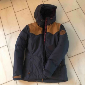  -  Varm skidjacka i mörkblått med ljusa skinndetaljer från Peak Performance. Använd på sin höjd 5 gånger. Figursydd modell. 