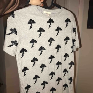  - Cool T-shirt med glittertryck i form av åskmoln.                     Säljes för 40kr exklusive frakt. Möts upp i Sthlm🌩