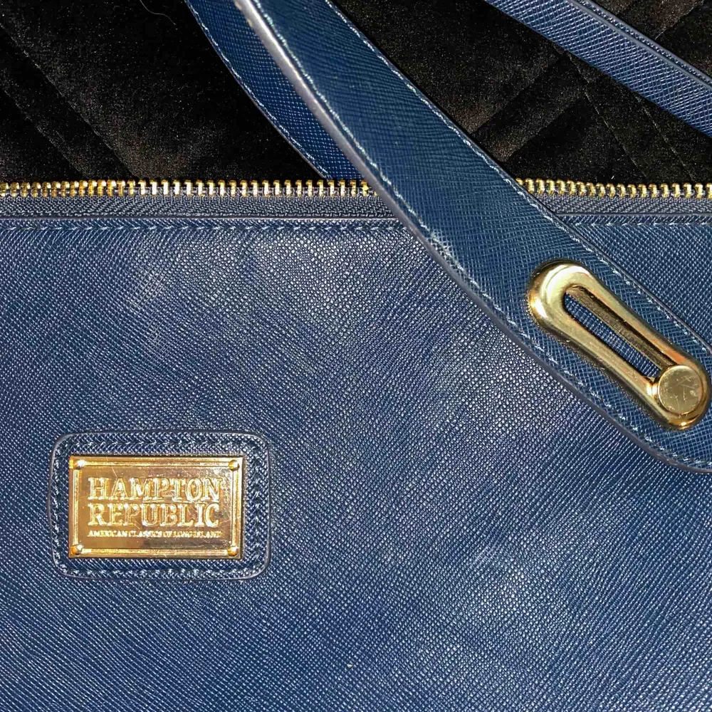 Mörkblå rymlig väska från Hampton Republic, med gulddetaljer. Köpt på Kappahl för några år sedan. Den är knappt använd men har legat ett tag i garderoben. Frakt tillkommer. Väskor.