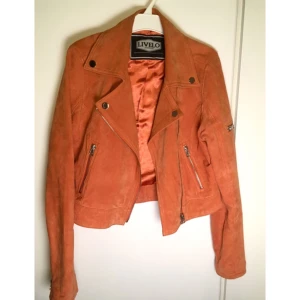  - Mockajacka i härlig orange färg! Jackan är i nyskick och har endast burits inomhus. Storleken är oklar då lappen verkar ha mystiskt försvunnit men jag brukar ha storlek S eller 36 i kläder och den är i tightaste laget för mig. Vill du bära den öppen som en sommarjacka fungerar det ännu bättre. Armlängd ca 60cm. Portot betalas av köparen.