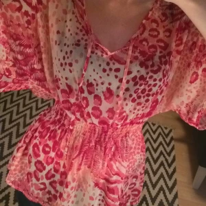  - Färgstark tunika/blus från HM. Grymt skönt tyg och passform, passar till vardags och fest. Den har resår i midjan så att midjan framhävs, det går att knyta vid bröstet, men jag brukar låta det hänga. Röd, mörkrosa, ljusrosa samt lite vit i ett häftigt mönster. Köparen betalar frakt!