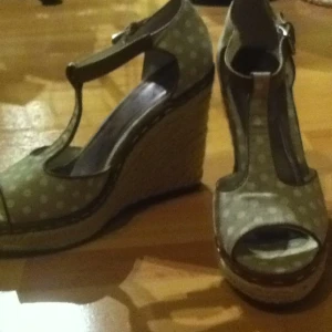  - Sko med kilklack. Grå, vit prickiga med bruna detaljer och flätat rep runt klacken. Använda en gång. Köparen betalar frakten.