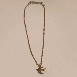  - Fint och enkelt guld halsband med en fågel. Justerbar kedja. Fint skick. 