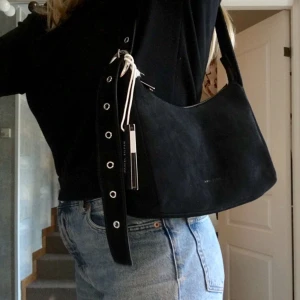  - Säljer denna jättesnygga svarta väska i mocka från märket Daniel Silfen. Inköpt på Nelly för 1099kr. Aldrig använd, säljes pga att jag redan har för mycket väskor. Väskbandet kan justeras så att den både kan användas som en crossbody väska eller över axeln.