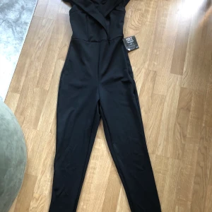 Byxdress NLY - Svart byxdress från Nelly. Den andra bilden är endast för att visa passformen! Prislappar kvar, aldrig använd!