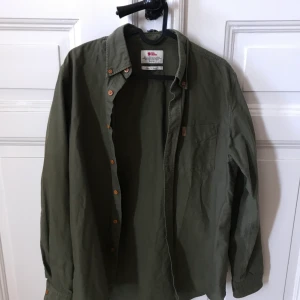 Militärgrön skjorta från Fjällräven - Skjorta från Fjällräven i strl S, herrmodell men passar unisex! Ljusbrun logga samt knappar. Jätteskön och sitter jättefint på! Säljer då den inte kommer till användning. 