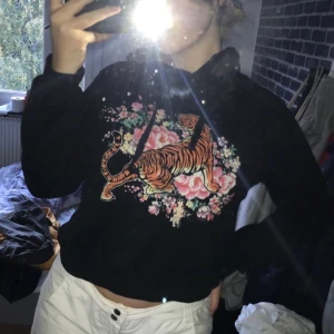 Svart hoodie med tigertryck - Säljer min svarta hoodie med coolt tigertryck eftersom den är för liten för mig. Köpt på second hand men kommer ursprungligen från Gina tricot. Storlek xs. 
