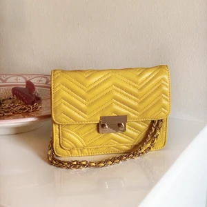 Axelväska från Mango - Trendig axelväska med gulddetaljer i nyskick. Bandet går att länga