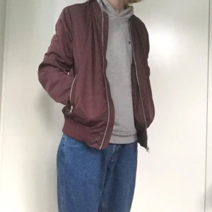 Dark Red Bomber Medium size Men’s - Vinröd bomber jacka I nyskick. Passar bra med hoodie under och är mer utav en skal jacka som man slänger på sig utanpå. Jag på bilden är 180cm lång för referens.