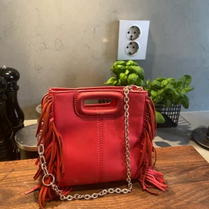 Röd Maje-väska - säljer denna fina maje väska pga att jag inte använder den så mycket längre! den är röd och i den minsta storleken. bra skick, enbart mindre slitage på handtaget och fransarna. nypris: ca 2400 kr. båda kedjorna medkommer!❤️