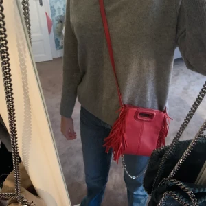 Maje väska  - Säljer min röda Maje väska i den lilla modellen då den inte kommer till användning. Den är köpt i somras och använd ett fåtal gånger så väskan är i toppskick! Om du är intresserad eller vill ha fler bilder så kontakta mig. Nypris 2400kr. Både kedjan och bandet medkommer plus dustbag 💞