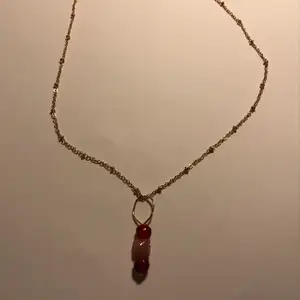 Guld halsband med röda och råsa stenar