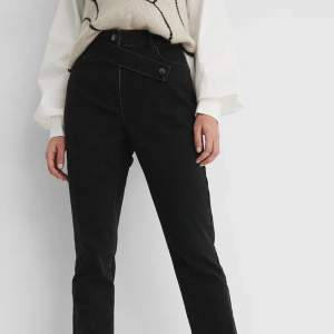 Säljer ett par helt oanvända, raka svarta denim jeans med hög midja, slits nertill och detalj upptill. Storlek 34.