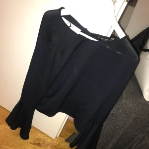  - Svart blus med öppen rygg och knyte i bak.