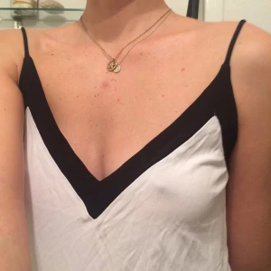  - Vitt linne med svarta kant som faller snyggt. Tunna band.  Upphämtning eller frakt 