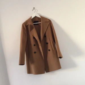  - Superfin kamelfärgad kappa från Massimodutti. Köpt i London förra hösten och använd 1-2 gr på grund av att jag spontanköpte den och inte har haft användning för den. Storlek 36. Helt som ny förutom att "hängremmen" högst upp har lossnat - eftersom den bara hängt ett år... nypris drygt 2000kr