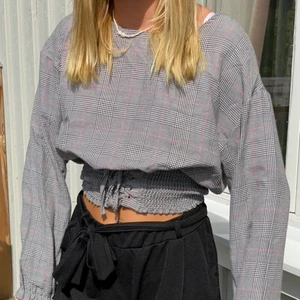 Rutig grå blus med korsett - En rutig tröja med korsett, bra skick och okej passform. Går att knyta och dra åt korsetten om man så önskar. 