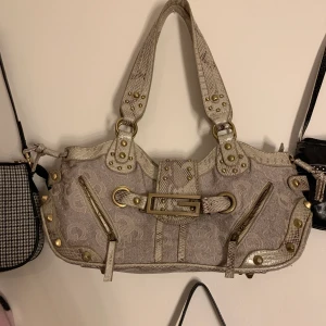 Guess väska - En skitsnygg 90s handbag från guess! Säljer för brist på användning. Det enda felet är att en pärla lossnat(2a bilden) annars är den i toppen skick. Säljer för 160kr+ frakr , svarar ej om du vill köpa för lägre(ingen budgivning, säljer direkt helst)