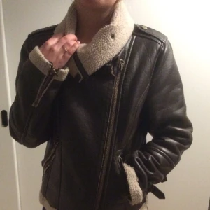  - Varm fodrad jacka i brunt imitationsskinn.
Passar S om man vill ha plats för tjock tröja under men på lappen står det strl M. 
Använd men i bra skick, lite trasig vid dragkedjan men det är inget man ser eller tänker på  (se bild) , annars är det lätt fixat.
