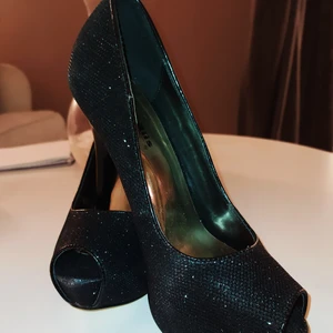 Svarta klackar i princip oanvända - Strl 38, ca 1 cm platå och klackhöjd typ 11 cm. Inga slitningar på klackar eller sulor.