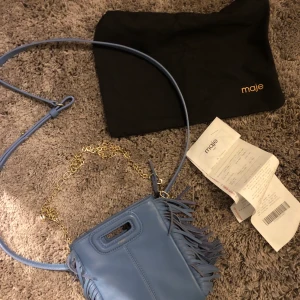 Maje väska - Intressekoll på min superfina majeväska! Lilla modellen i jättefin blåfärg, långt band, kedja, dustbag och kvitto medföljer! Jättefint skick, inga tecken på användning alls! Nypris: 2150kr