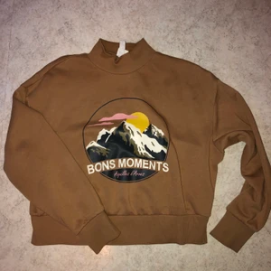 Brun Tröjamed tryck - Snygg, ganska croppad och superskön brun tröja. Det är halvpolo och sitter perfekt på dig som har strl S-M