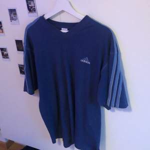 En blå vintage adidas t-shirt köpt på humana för ett halvår sedan. Nypris var ca 200kr. Den är i ganska gott skick trots second hand. Storleken är M, däremot kan det bero på hur man vill att den ska sitta :)