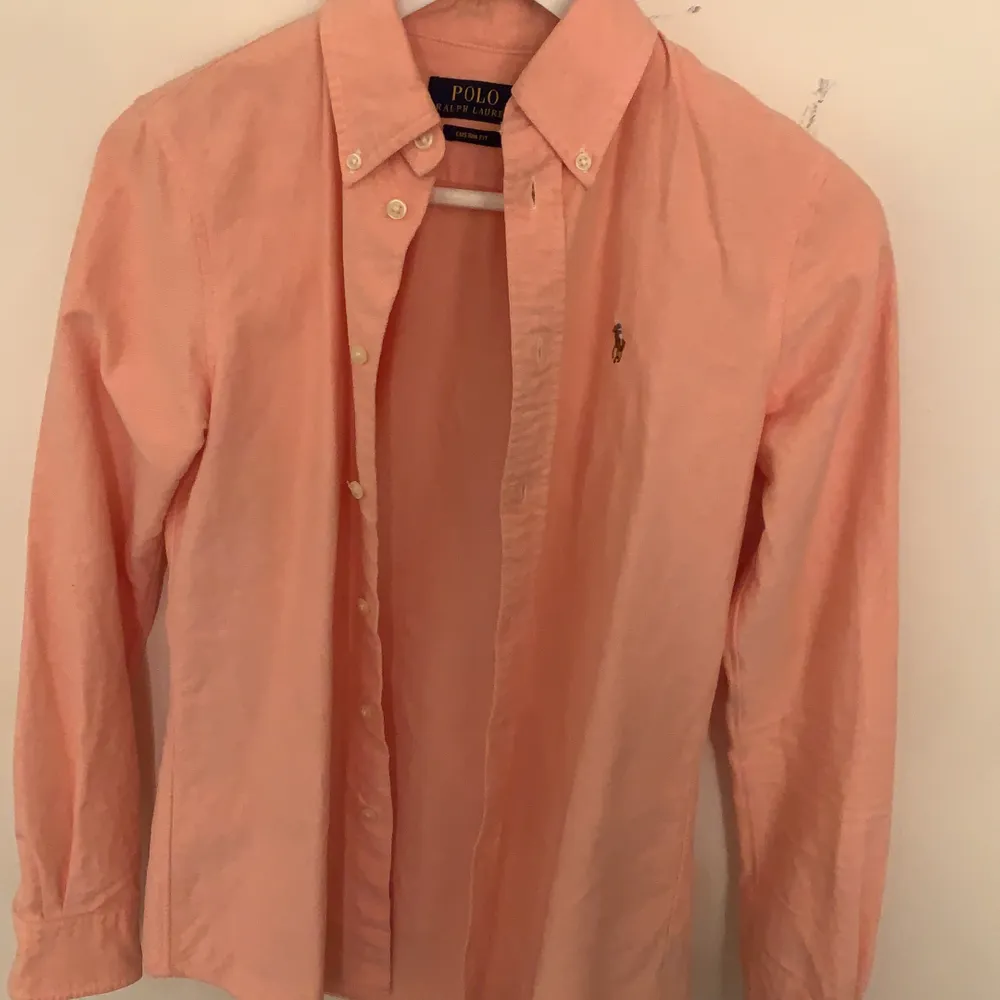 En persikofärgad skjorta från Polo Ralph Lauren i strl XS. Endast använd ett par gånger så i bra skick. Säljer då den aldrig används.. Skjortor.