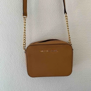  - Ljusbrun Michael Kors väska i gott skick, använt fåtal gånger men tyvärr fått ett litet märke av en penna uppe på höger sidan av väskan. 
