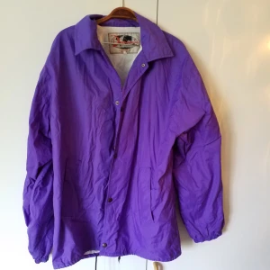  - Lila regnjacka i storlek L, passar andra storlekar också beroende på hur man vill ha den