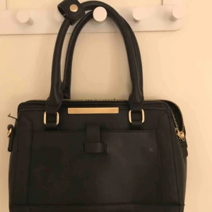  - Den har många fack med gulddetaljer, eftersom den har många fack och bra förvaring så är den perfekt till handbagage eller också en vardaglig handväska, köpt den för 200kr och den ytterst lite sliten men syns knappt