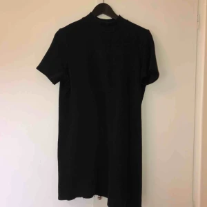  - Kort, svart klänning med stor mudd i kragen