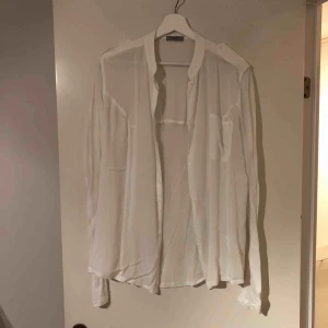  - Vit skjorta från Hunkydory, tight passform i ärmarna som är gjorda i ett tunt tencel material. Samma tyg återfås på baksidan av plagget. Den främre delen är gjord i viscose. Faller väldigt fint på kroppen, sparsamt använd! 