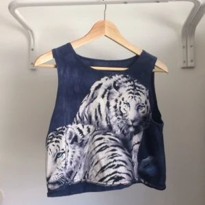  - Supersnyggt mörkblått kort linne med två vita tigrar tryckt på framsidan. Linnet har lös passform. Beroende på hur man vill att den ska sitta kan den även passa XS och M.   Frakt ej inkluderat i priset. 