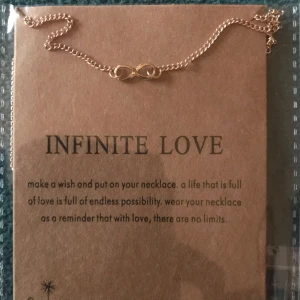  - Guld pläterat halsband med symbolen för infinitiv love  samt en text till . 